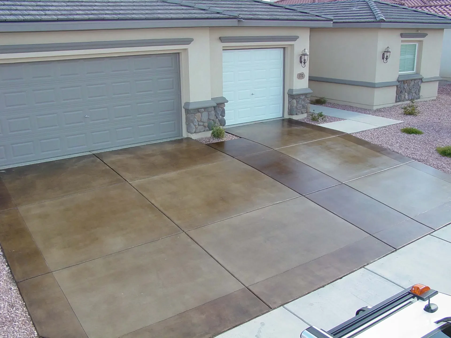 Two-tone stained and sealed concrete driveway in front of a tan stucco house