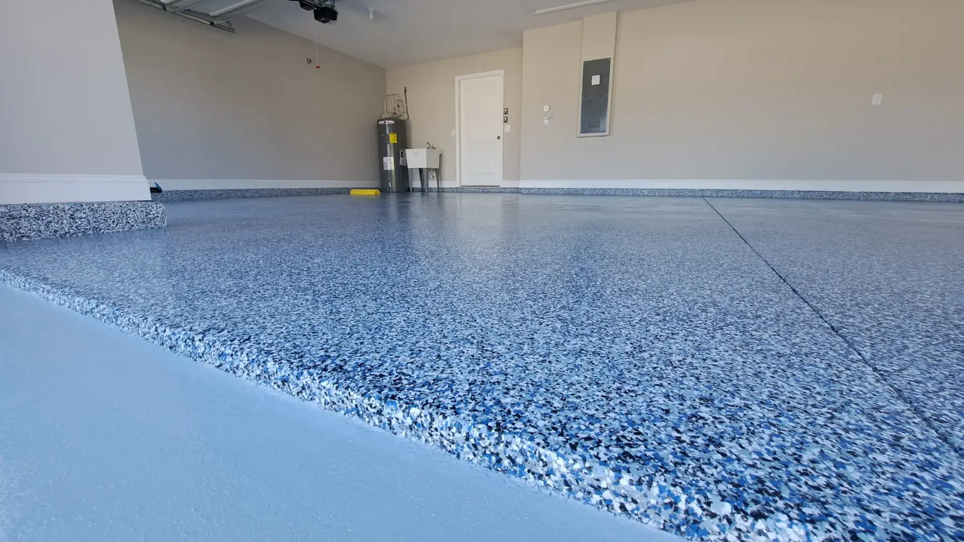Blue and gray flake epoxy garage floor with the flake run up the wall as a cove base