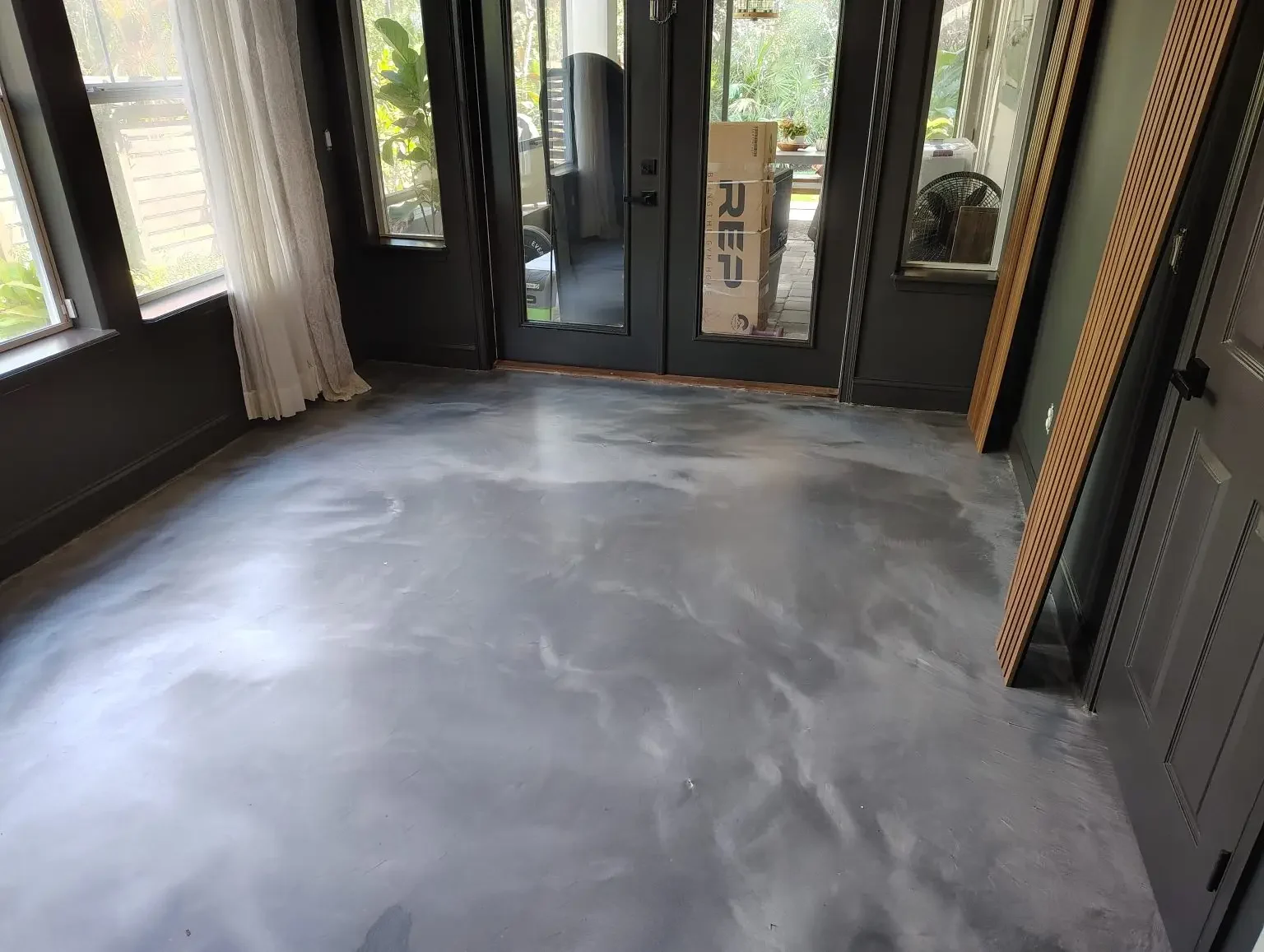 Silver gray metallic epoxy floor inside French doors with dark trim