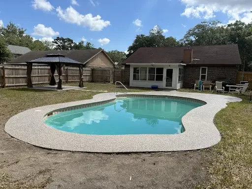Flake coated deck edging a kidney-shaped pool in a fenced backyard